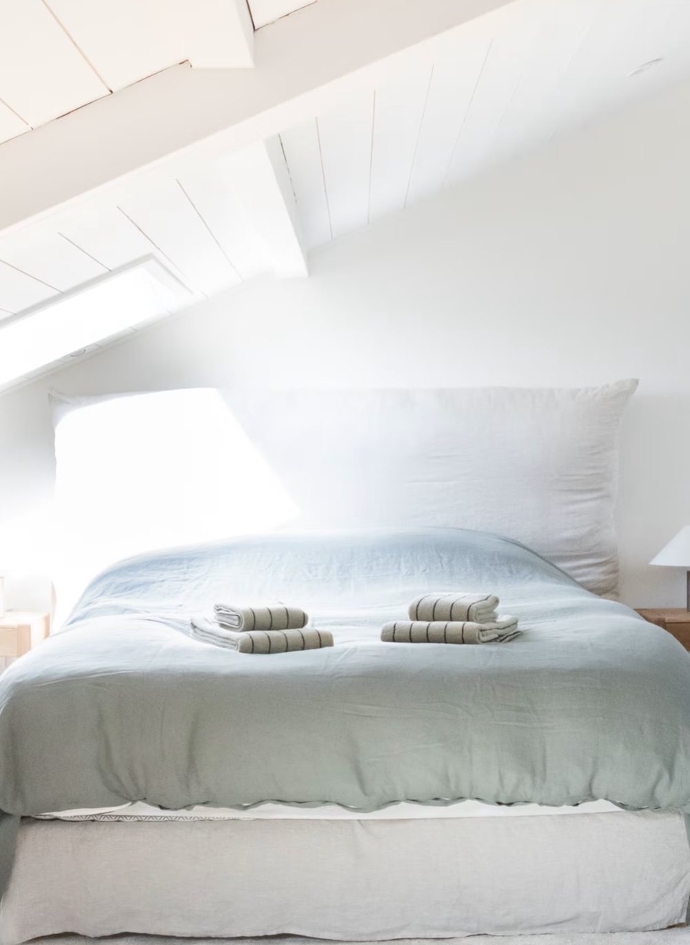 Chambre sous combles, linge de lit vert d'eau et lumière de toit